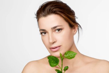 Taze yeşil yapraklı doğal güzellik ve cilt bakımını vurgulayan bir kadın portresi. Kopyalama alanı olan hafif arkaplan.