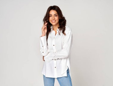 Gri arka planda gülümseyen güzel esmer kadın.