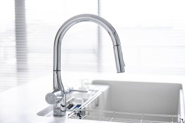 Stainless steel faucet in white kitchen clipart