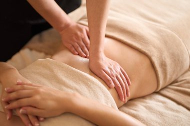 A woman receiving a belly massage at a beauty salon clipart