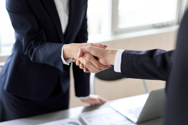 Male and female Asian business people shaking hands