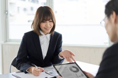 Tableti gösteren ve açıklayan Asyalı iş kadını