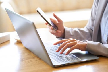 Kafede bilgisayar kullanan Asyalı bir kadının eli.