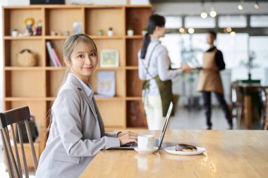Kafede bilgisayar kullanan Asyalı bir kadın.