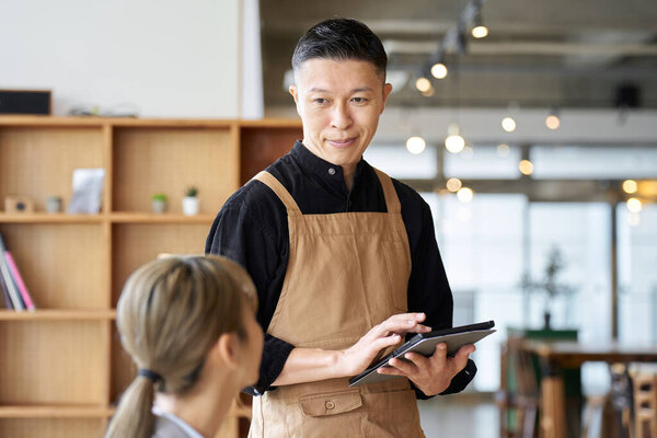 Asian male clerk taking orders at a cafe