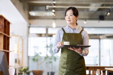 Restoranda atıştırmalık taşıyan Asyalı bir çalışan.
