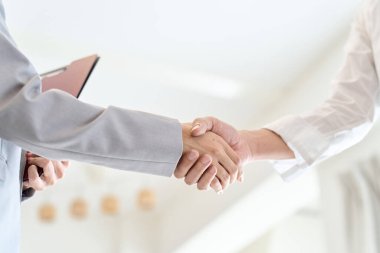 Bir erkek ve bir kadın emlak anlaşması yaptıktan sonra el sıkışıyor.