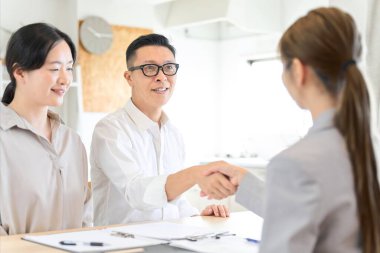 Asyalı adam sigorta sözleşmesiyle el sıkışıyor