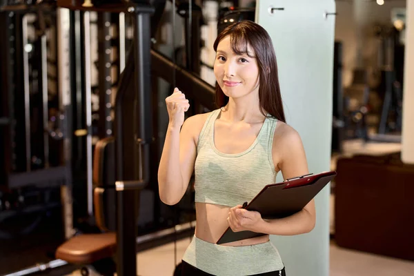Female personal trainer doing fist pump at fitness gym