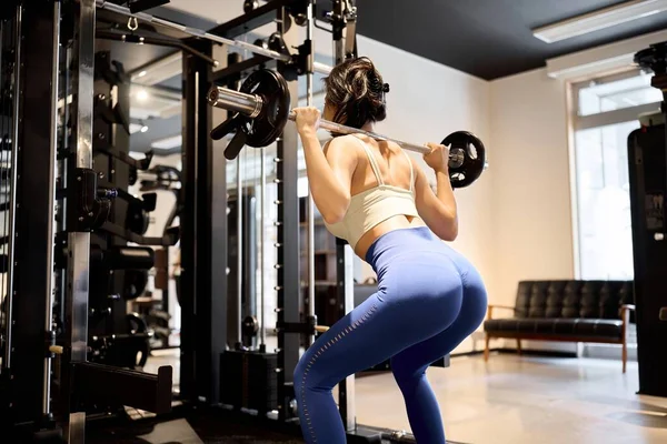Woman training her lower body with barbell squats