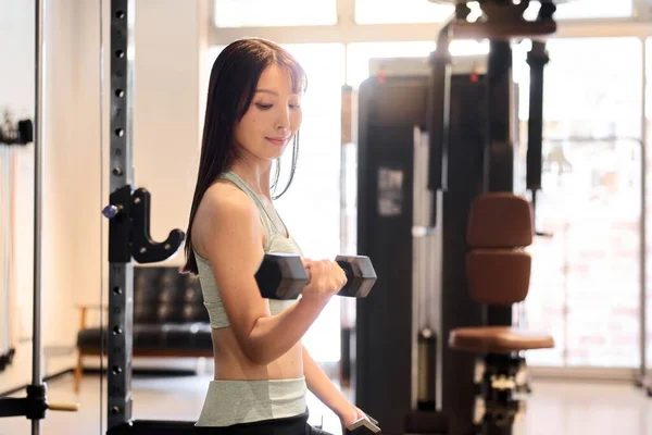 Woman training her arms with dumbbell arm curls