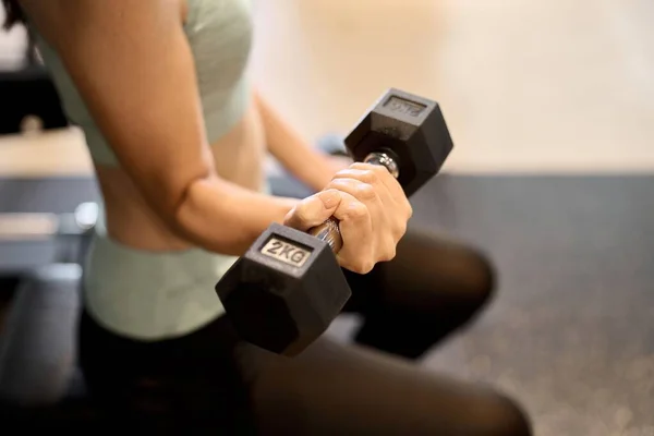 Woman training her arms with dumbbell arm curls