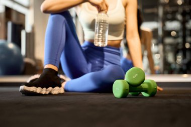 Spor salonunda antrenman yapan bir kadının resmi.