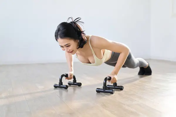 Woman doing push-ups using a push-up bar