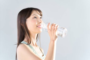 Plastik şişeden su içen bir kadın.