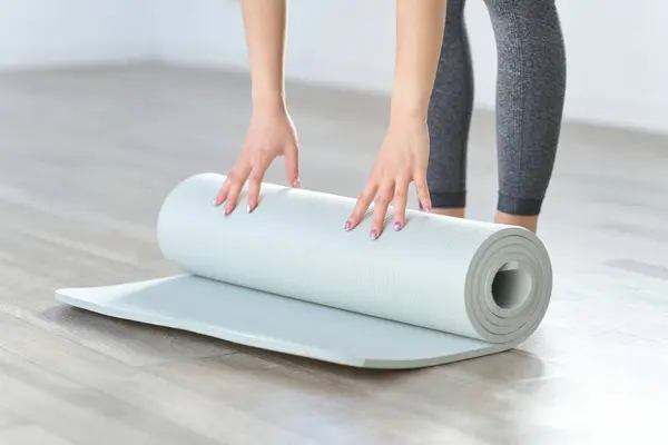 Hands of a woman spreading out a yoga mat