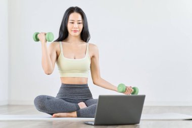 Bir kadın video izlerken kas antrenmanı yapıyor.