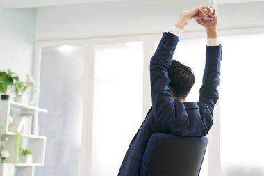 Çalışırken gerinen bir iş adamının arka görünüşü