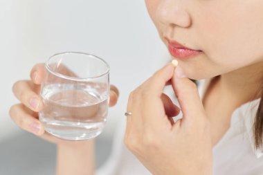 Asyalı kadın kapsül ilacı içiyor.