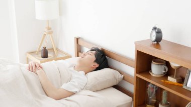 Bir adam çalar saati kurar ve uyur.