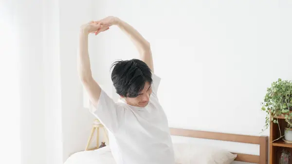A man wakes up and stretches