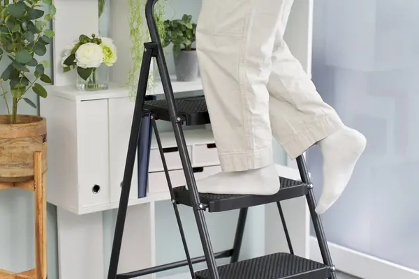 The feet of a man on a stepladder tidying things up