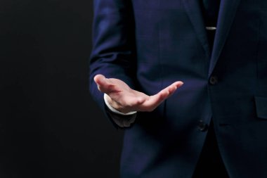 İşadamı elini siyah arka planda tutuyor.