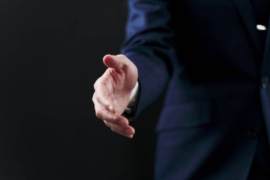 İş adamı siyah arka planda el sıkışmak istiyor.