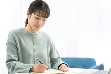 Kadın oturma odasında ders çalışıyor.