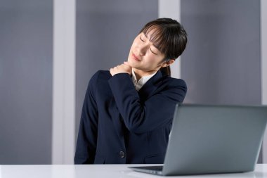 Fazla mesai nedeniyle omuzları tutulmuş bir iş kadını.