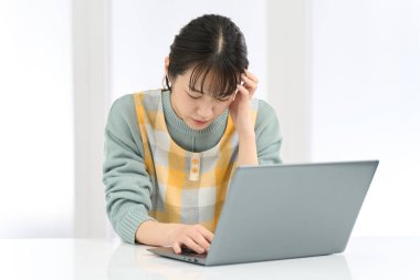 A woman wearing an apron holding her head while working on a computer clipart