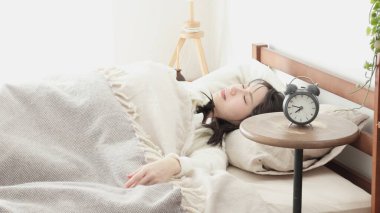 A woman who turns off her alarm and goes back to sleep clipart