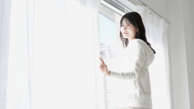 Sabah perdeleri açan bir kadın.