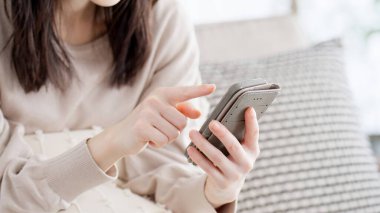 Oturma odasında akıllı telefona bakan bir kadın.