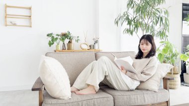 Kanepede kitap okuyan kadın.