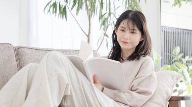 Kanepede kitap okuyan kadın.