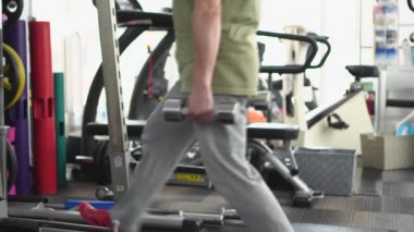 Bir adam alt vücudunu halterle eğitiyor.