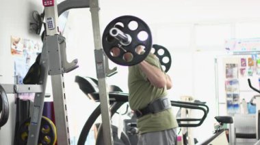 Adam alt vücudunu halterle eğitiyor.