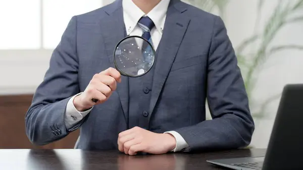 Stock image Businessman raising a magnifying glass to his chest