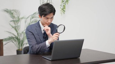 Büyüteçle araştırma yapan bir iş adamı.