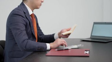 Banka defterindeki miktarı hesaplayan bir iş adamının elleri.