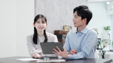 Bir tabletteki emlak bilgilerine bakan erkek ve kadınlar