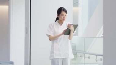 Gülümseyerek tablet kullanan bir hemşire.