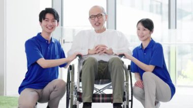 Tekerlekli sandalyedeki yaşlı kişi bakıcısıyla konuşuyor.