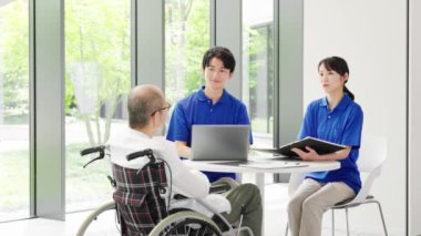 Bir bakıcı yaşlı birine açıklama yapar.