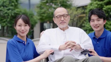 Gülümseyen bakıcı ve tekerlekli sandalyedeki yaşlı kişi