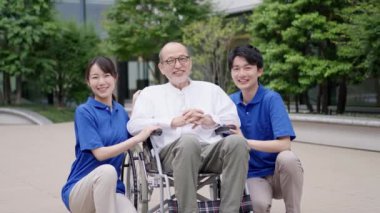 Gülümseyen bakıcı ve tekerlekli sandalyedeki yaşlı kişi