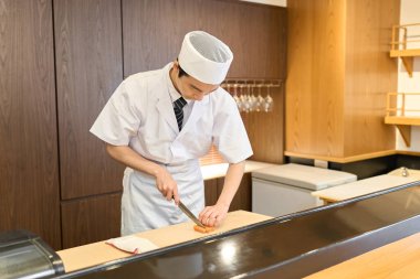 Japon aşçı mutfakta yemek pişiriyor.