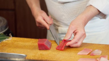 Kırmızı ton balığı kesen bir suşi şefinin elleri.