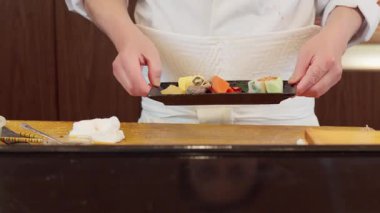 Japon bir şefin elleri yemek sunuyor.